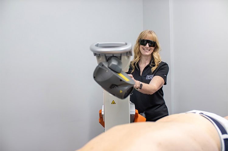 OrthoLazer specialist operating a laser during lower back treatment