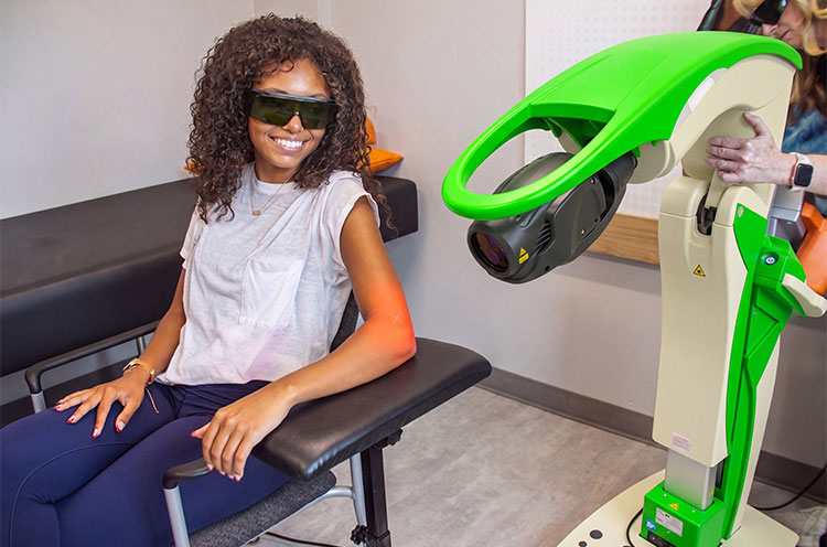 Patient receiving OrthoLazer laser therapy on her arm with the green laser system