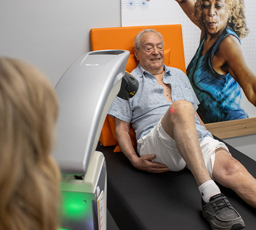 Older patient receiving OrthoLazer laser therapy on his knee