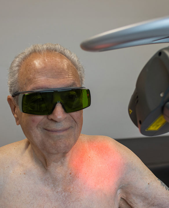 Older OrthoLazer patient receiving laser therapy on his shoulder