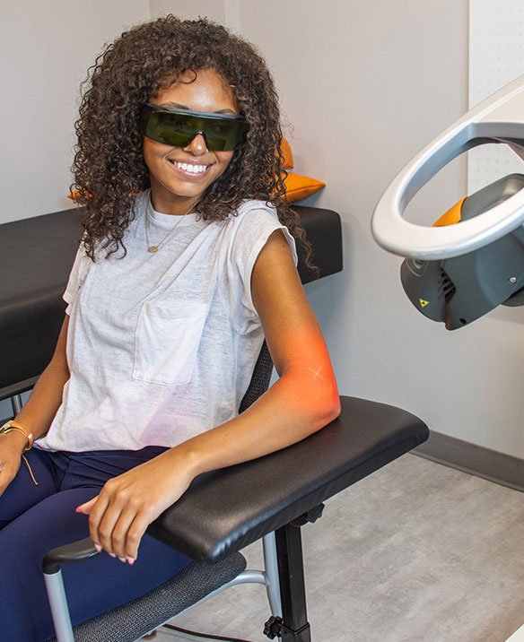 Smiling OrthoLazer patient receiving laser therapy on her arm